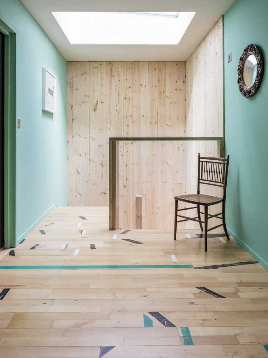 Dursley Treehouse interior hallway with timber-clad walls, reclaimed wood floor, skylight, and painted mint walls